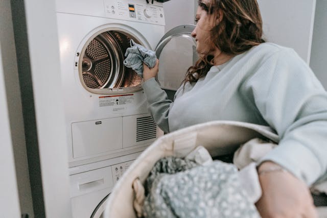 person holding a laundry hamper putting clothes into the washing machine
